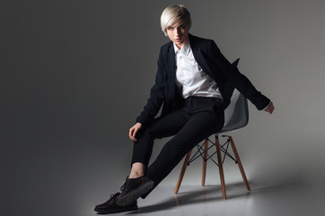 Blonde woman in fashion cloth sitting on the chair