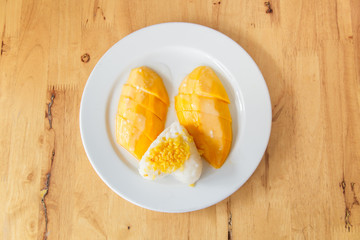 Mango sticky rice or khao niao mamuang is a Thai dessert made with glutinous rice on wood
