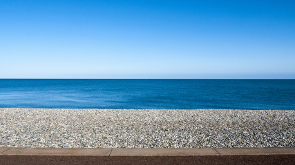 Seascape with pebble stone beach and sea defence wall on a beautiful day in Llandudno Wales UK