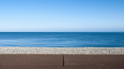 Seascape with pebble stone beach and sea defence wall on a beautiful day in Llandudno Wales UK