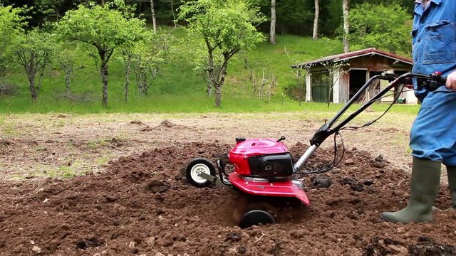 Farmer plowing the field with rototiller.