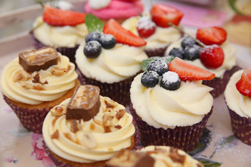 Delicious vanilla cupcake with strawberry frosting and fresh strawberries and blueberries