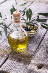 Jug with extra virgin olive oil on cutting board surrounded by branches