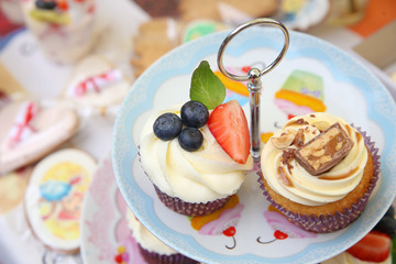 Delicious vanilla cupcake with strawberry frosting and fresh strawberries and blueberries