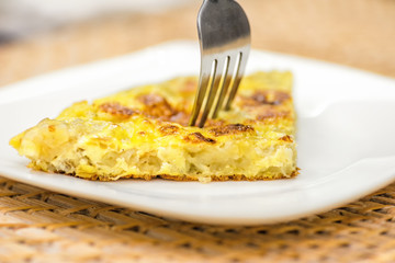 Slice of Spanish Tortilla with a Fork on a white dish