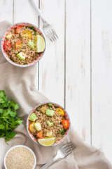 Quinoa with tomatoes, zucchini and lime on white wooden table
