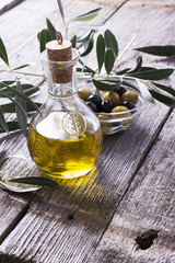 Jug with extra virgin olive oil on cutting board surrounded by branches