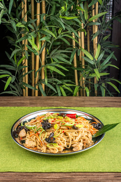 Close-up of tasty pasta with mushrooms and chili peppers on a metal plate
