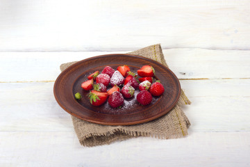 strawberries with sugar on a clay plate