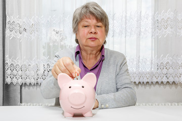 Besorgte Seniorin steckt Geld ins Sparschwein