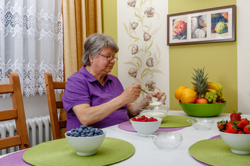 Seniorin füllt Joghurt in eine Schale