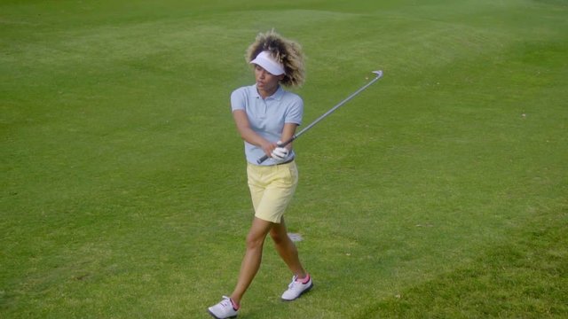 Pretty young woman golfer strolling on the golf course with her club over her shoulder as she follows up on her ball  with copy space