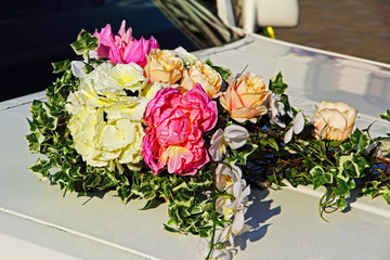 Decorative flowers bouquet on white wedding car.