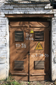 old metal brown doors of old white brick building of transformer