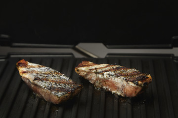 two pieces of salmon roasted close up on home electronic grill plate tasty diet fish meal