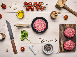 Healthy foods, cooking concept home cooking burgers, mince in a small frying pan, herbs, oil, kitchen knife and a hammer, a top view