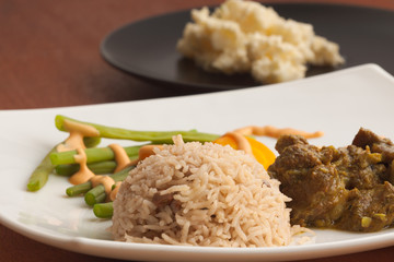Curried Goat served with Rice & Peas, vegetables and homemade potato salad.