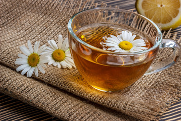 Obraz na płótnie Canvas cup of chamomile tea with chamomile flowers and lemon