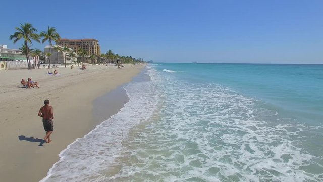 Man running along the coast. Aerial footage of Hollywood beach, Florida, USA Flying in paradise)