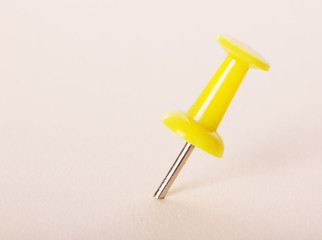 Yellow pushpin on  light pink background.