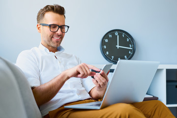 Young man using his smartphone for online banking - sitting on s