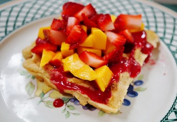 Freshly baked Belgian waffle with fresh fruit and berry coulis