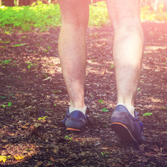 Rear view low angle view of man legs, walking in forest.