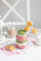 Smoothie with cottage cheese, strawberries and spinach in a glass jar with small cheese pancakes on a white table. Selective focus.