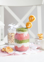 Smoothie with cottage cheese, strawberries and spinach in a glass jar with small cheese pancakes on a white table. Selective focus.