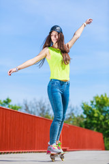 Teen girl skater riding skateboard on street.