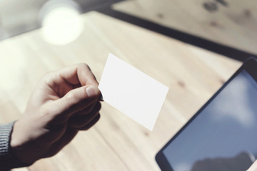 Closeup Man Showing Blank White Business Card, Holding Hand Modern Digital Tablet.Wood table Blurred Background.Mockup Ready Private Information.Sunlight Reflections Screen Gadget.Horizontal mockup.