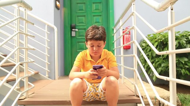 Young boy using smartphone and smiling to camera