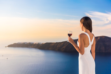 Young woman drinking red wine on outdoor terrace watching beautiful sunset view of Mediterranean...