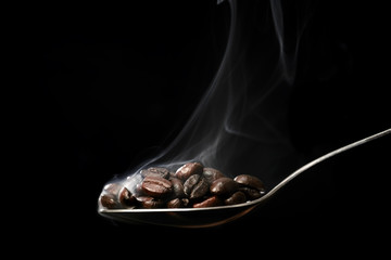 Scooping hot coffee beans with spoon.