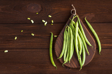 bean pods on cutting board on wooden background