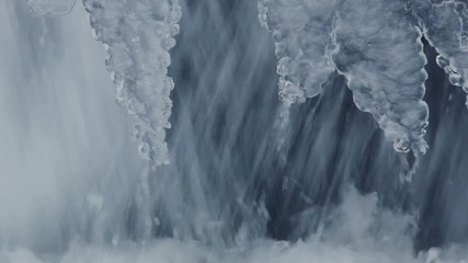 Nature background. Small waterfall in winter. Water flowing in winter. Fast water flow. Flowing water. Closeup. Icicles and running water. Icy waterfall close up. Abstract background. Water splashes - Powered by Adobe
