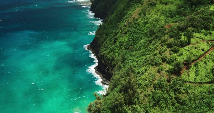 Aerial view flying over lush tropical coastline sea cliffs and jungle. Na Pali Coast Trail, Kauai