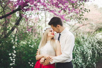 Stylish beautiful happy wedding couple kissing and embracing in Botanical Garden