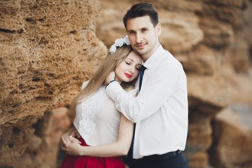 Romantic loving couple walking on the beach with rocks and stones