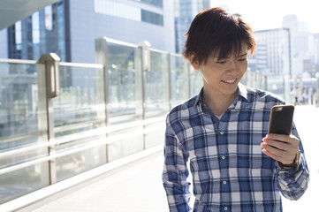 Young man is walking while looking for a destination in the smartphone