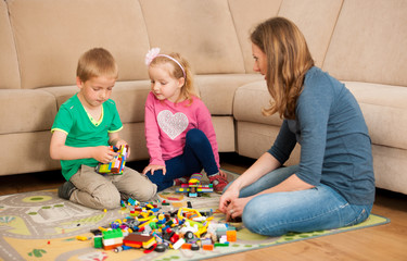 Children and their mother are playing with blocks on the ground