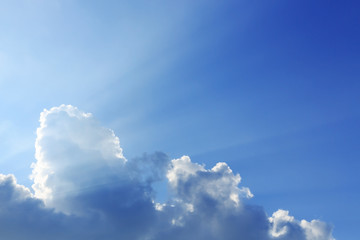 sunbeam of sunlight through clouds on clear blue sky