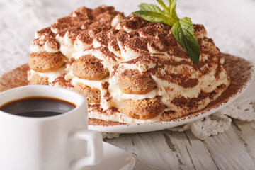 Italian Tiramisu cake on a plate and cup of black coffee close-up. Horizontal
