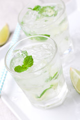 Non alcohol cold mojito cocktail with fresh lime, mint and crushed ice on a kitchen background, closeup
