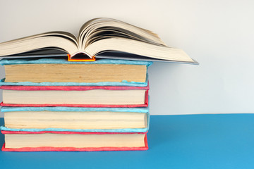 Open book, stack of colorful hardback books on light table. Back to school. Copy space for text