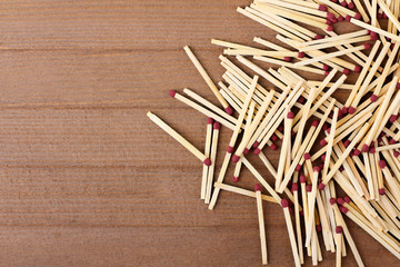 new matches scattered on a brown wooden background