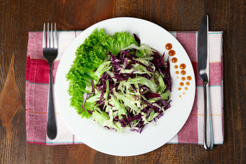 chopped cabbage in the dish by the Cutlery on the cloth on a wooden table