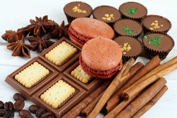 candies and chocolates with cinnamon and anise with coffee beans on wooden white background