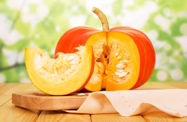 Orange cut pumpkin with seeds, and slice on abstract green.