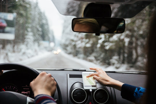 Hands of couple driving and using navigation on mobile phone